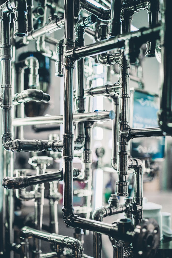 about-us-01 Close-up of complex stainless steel pipes in an industrial setting, showcasing modern engineering.